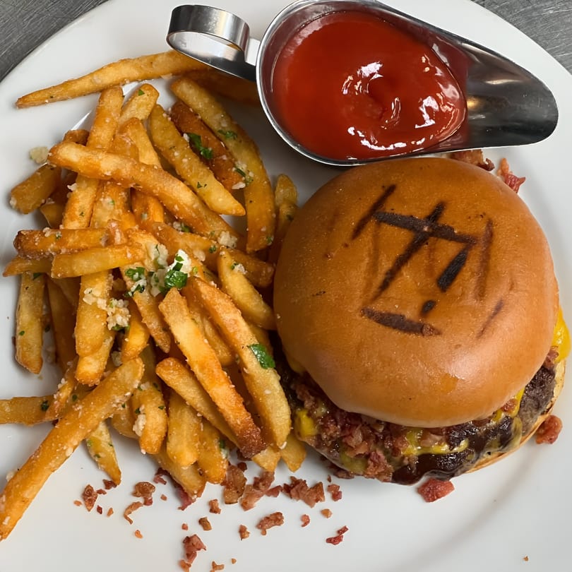 A Davinci's bacon cheeseburger with a branded bun, garlic parmesan fries, and a side of ketchup.