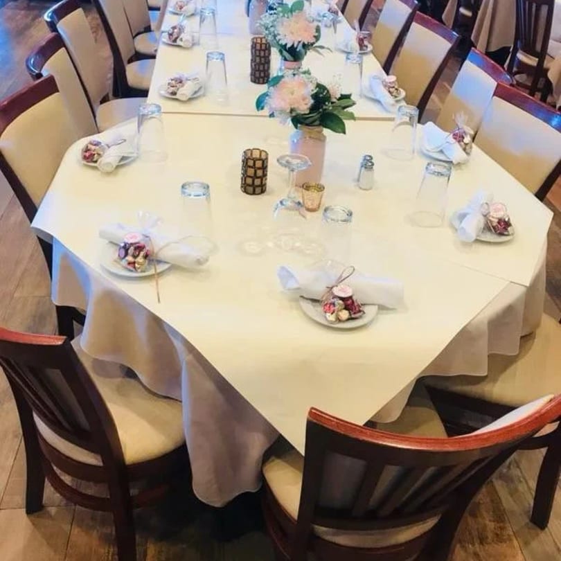 A long dining table set with white tablecloths, floral centerpieces, and place settings for a Davinci's event.