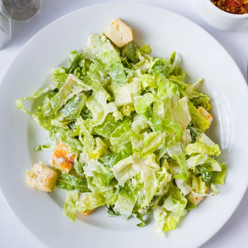 Davinci's Caesar salad with crisp romaine lettuce, creamy dressing, and golden croutons on a white plate.